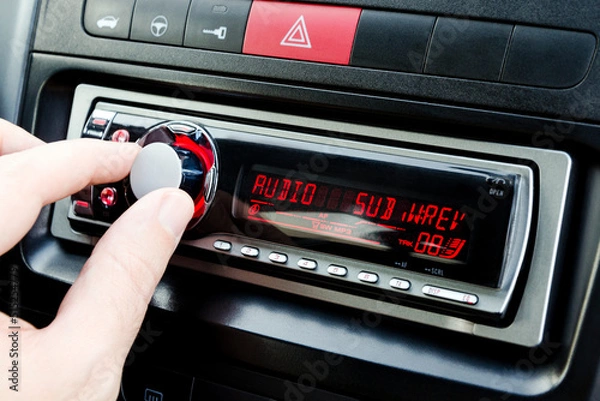 Fototapeta Car audio player and man`s hand. Adjustment player. Closeup view