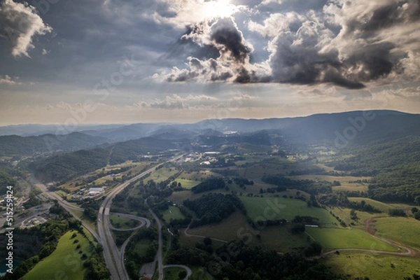 Fototapeta Highway cutting through Farmland with Mountains and Dramatic Clouds