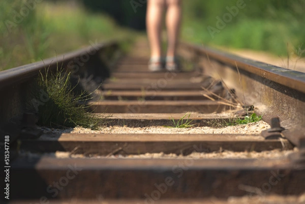 Fototapeta Closeup of a person walking on the railway on a sunny day - new opportunities