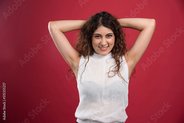 Obraz Woman holding hands behind the head on red background