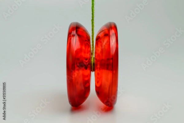 Fototapeta Red plastic yo-yo toy isolated on White Background with green rope attached to it.