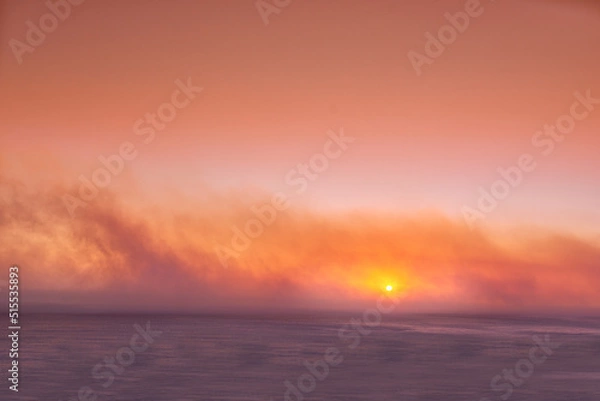Fototapeta Seascape of a beautiful golden sunset with copy space. Sun setting on the horizon of a calm ocean at dusk or twilight. The calm and tranquil ocean or sea in the evening with bright sky copyspace