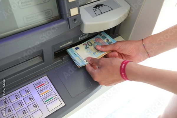 Obraz hands taking 20 Euro bills from an ATM machine after typing the code