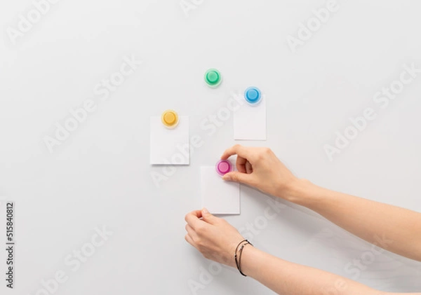 Obraz Image of white board and hand attaching pieces of paper to the magnetic board.