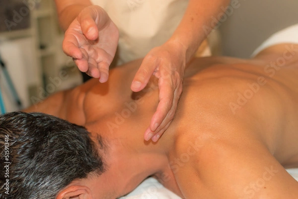 Obraz man receiving therapeutic massage by percussion on the upper back area