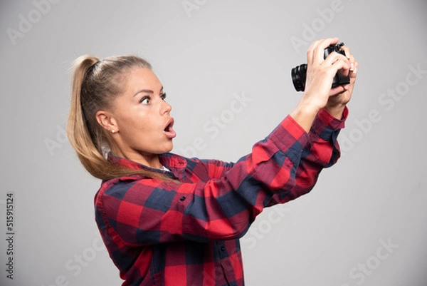 Fototapeta Blonde photograph in checked shirt makes surprized face and takes her own photos