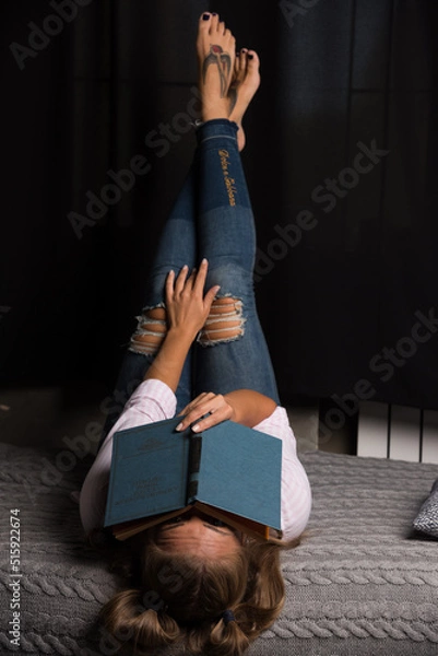Obraz Woman lying on bed and put book on her face on dark background