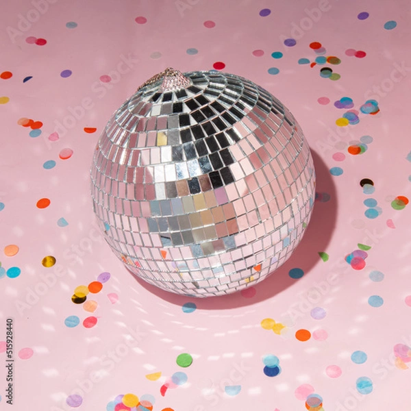 Fototapeta Shiny disco ball and colorful confetti on pastel light pink background. Trendy party symbols concept. Minimalistic celebration composition.