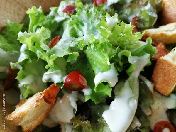 Obraz Fresh tomatoes with cucumber, lettuce, red onion and spices in a white bowl. 