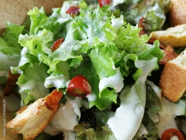 Obraz Fresh tomatoes with cucumber, lettuce, red onion and spices in a white bowl. 