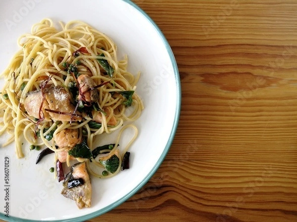 Obraz Spaghetti on black plate on wooden background. top view.