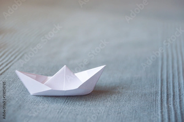Fototapeta White paper boat on a light blue fabric background 