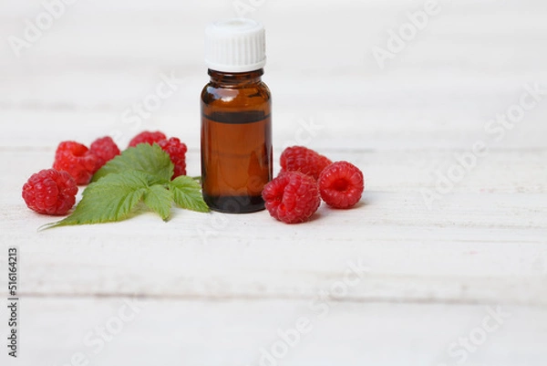 Fototapeta Red Raspberry (rubus idaeus) seed oil bottle with red raspberry and leave on white wooden background