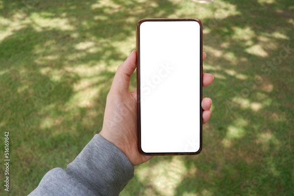 Fototapeta Mockup picture of business woman’s hands holding smart phone with white blank screen in modern place