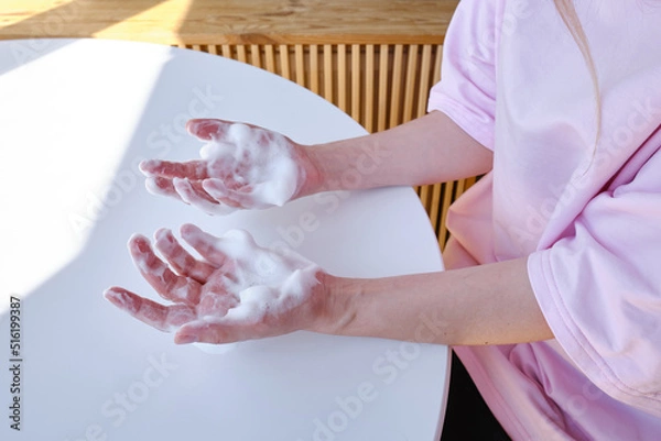Fototapeta Women's hands with soft soap or airy hand cream on a light background. Cosmetic care for hands and nails. Beauty and health
