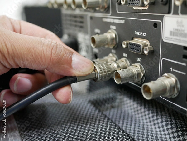 Fototapeta hand holding BNC SDI signal cables plugged connection in broadcast.