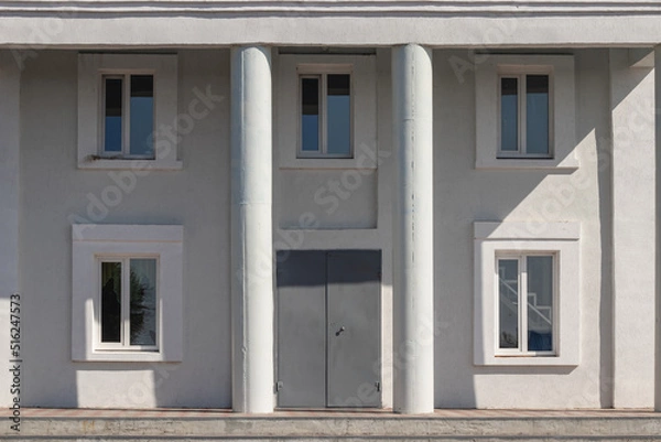 Fototapeta House wall texture with columns and windows with door on a summer sunny day