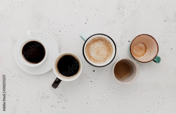 Fototapeta Top view on flat lay with many different full and empty coffee cups composition on gray white concrete background. Variety of tea mug collection layout. Dried coffee beans. Espresso, latte, americano