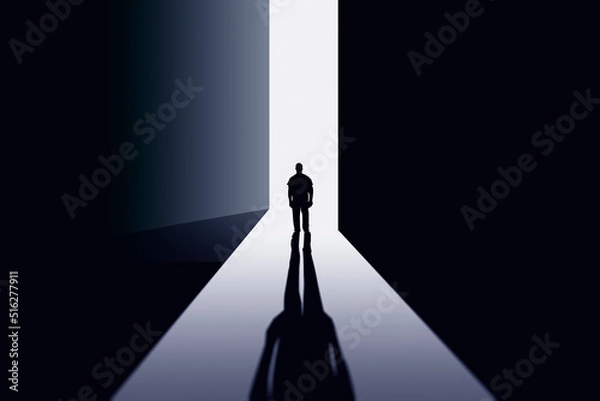Fototapeta A man stands in the doorway of a large ajar door in the rays of light.