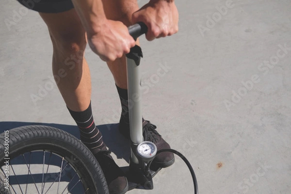 Fototapeta man inflates a bicycle wheel with a hand pump with a manometer