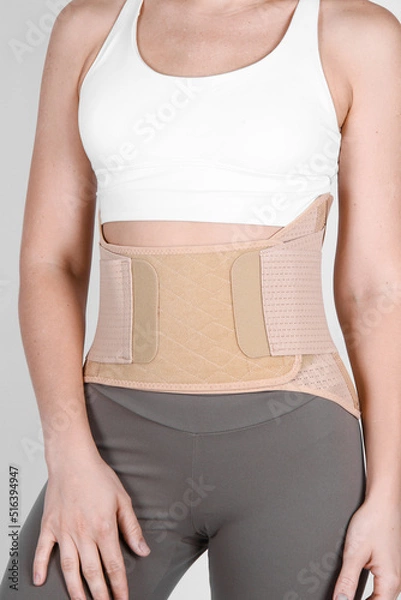 Fototapeta Orthopedic lumbar corset on the human body. Back brace, waist support belt for back. Posture Corrector For Back Clavicle Spine. Post-operative Hernia Pregnant and Postnatal Lumbar brace after surgery.