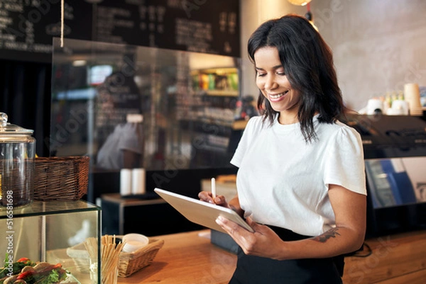 Fototapeta Happy waitress barista using digital tablet at work in cafe, restaurant