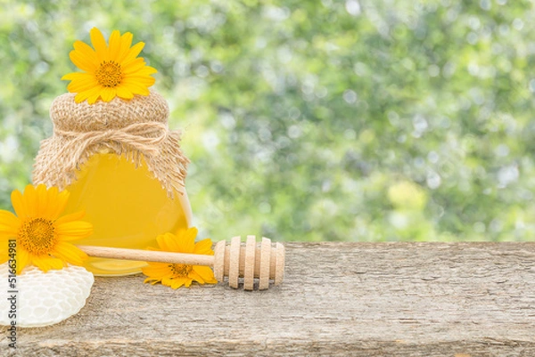 Fototapeta A jar of honey with flowers on a defocused background with copy space