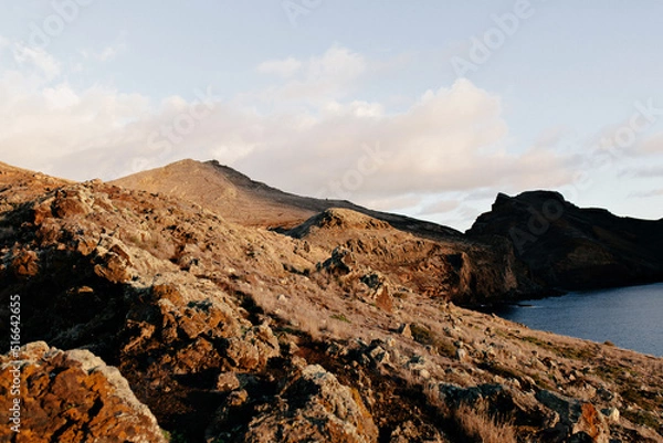 Fototapeta Wild nature. Rocky red mountains on the background of Atlantic ocean in sunlight. Beautiful view. 