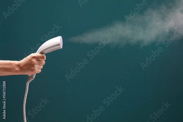 Obraz Close up view of male hand with vertical steamer isolated on green background.