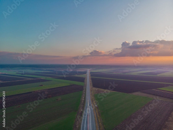 Fototapeta Straight road through the fields. Aerial photo.