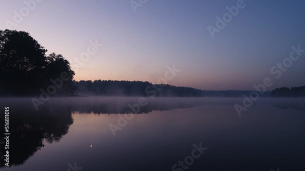 Fototapeta Beautiful mystical landscape. Forest lake at summer night before sunrise. Fog above calm water. Scenic nature.