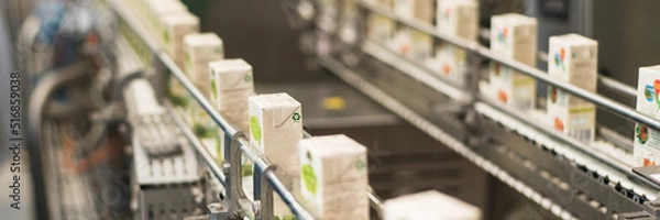 Fototapeta Conveyor at the plant for the production and bottling of juices in cardboard packaging. Web banner.