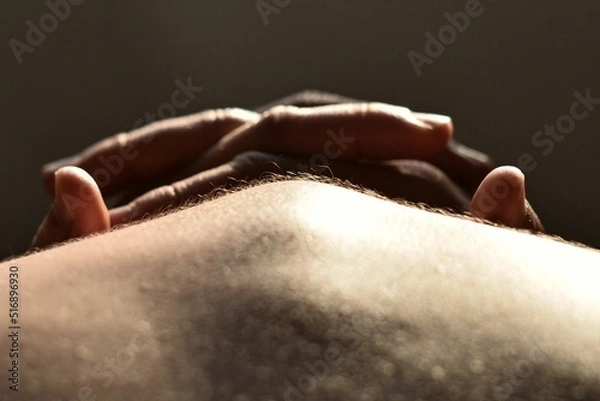 Fototapeta The human body in the backlight. Hairs on human skin. The line of the shoulders and spine. Shadows and light. Crossed fingers in the background.