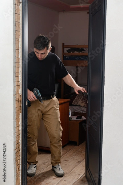 Fototapeta installation of a door handle using a manual screwdriver, assembly work.