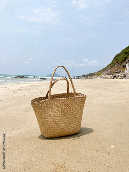 Fototapeta Photo of straw beach bag on exotic sand beach