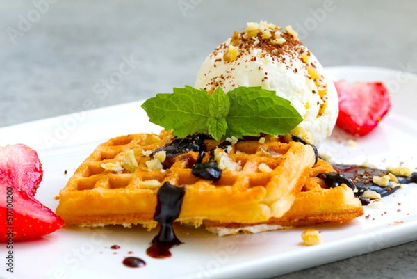 Fototapeta ice cream with Belgian waffles, strawberries, fresh mint, chocolate topping and nuts