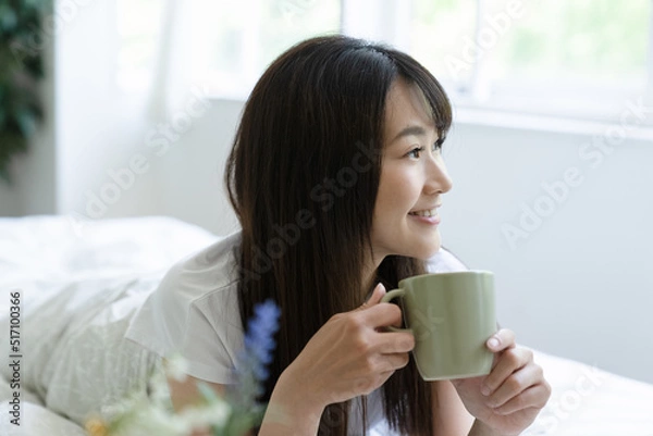 Fototapeta ベッドでスマホを見る女性