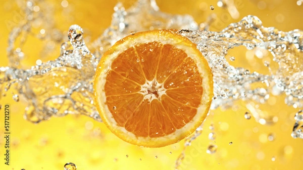 Fototapeta Slice of orange with water splashes on colored background.