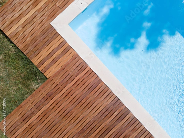 Obraz Drone flight over pool with nice wooden terrace surrounded by green lawn in beautiful garden