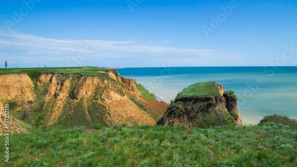 Obraz Ruined clay slope by the sea. Cracked clay cliff on the coast. A crumbling and cracked clay wall on the beach.