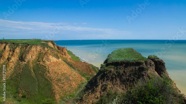 Obraz Ruined clay slope by the sea. Cracked clay cliff on the coast. A crumbling and cracked clay wall on the beach.