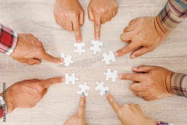 Obraz Close up Businesspeople hand holding jigsaw puzzle in a circle on the table, success and strategy concept.