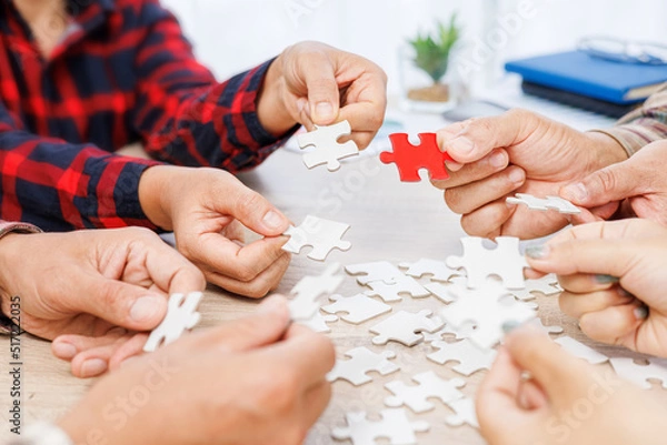 Obraz Close up Businesspeople hand holding jigsaw and jigsaw puzzle on the table, success and strategy concept.