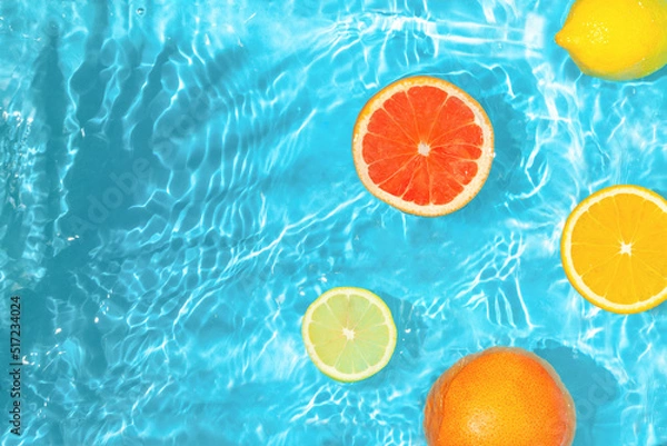 Obraz Refreshing sunny fruit scene with sliced citrus fruits and agitated blue water. Real summer nature. Creative copy space.