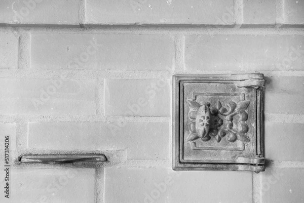 Fototapeta cast-iron oven door against the background of a brick oven wall as colorless background