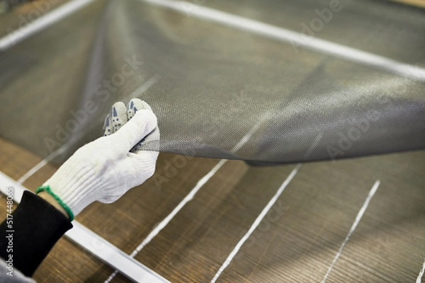 Obraz The hand of the worker who collects panels for protection from insects, holds a mosquito net for Windows.