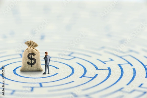 Fototapeta Reducing or overcome financial barrier, financial concept : US dollar bag on a maze puzzle with a businessman considers how to overcome financial difficulties. CFO wishes to avoid a financial crisis.