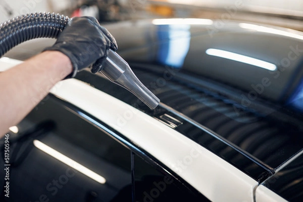Obraz Man worker drying car on a car wash. Service car wash express. Worker uses turbo dryer to remove drops of water. Car detailing, car wash, and paint correction concept. Close-up