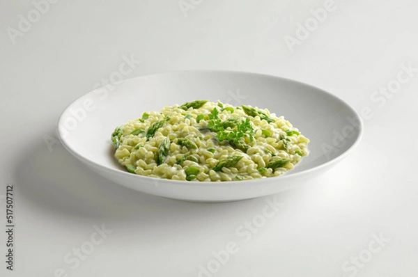 Fototapeta White bowl of risotto with green asparagus and parsley