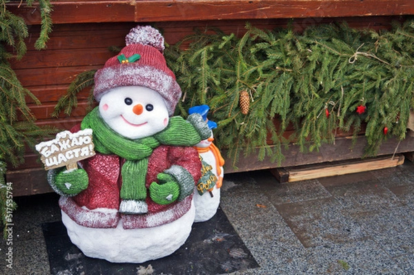 Fototapeta A figure of a snowman in a hat standing at a Christmas fair on a winter day